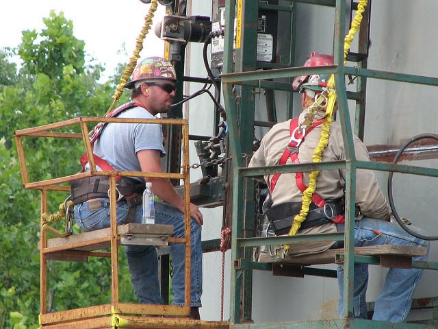 Welders monitor an automatic welding machine used to weld seams of the Fire Water Storage Tanks at the Blue Grass pilot plant.