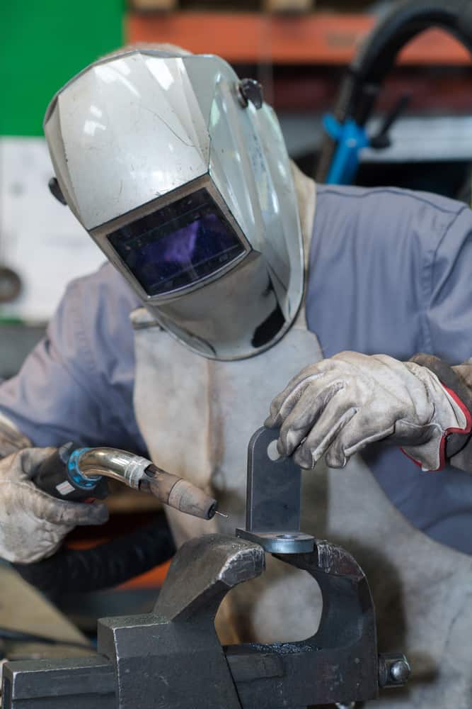 image of a welder in mask welding metal and sparks metal close