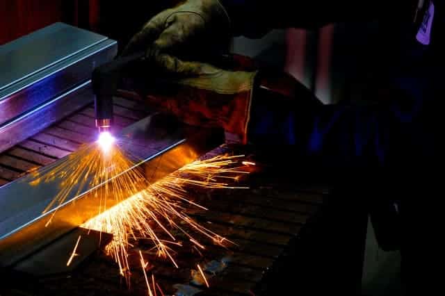 image of a worker cutting metal with plasma cutter