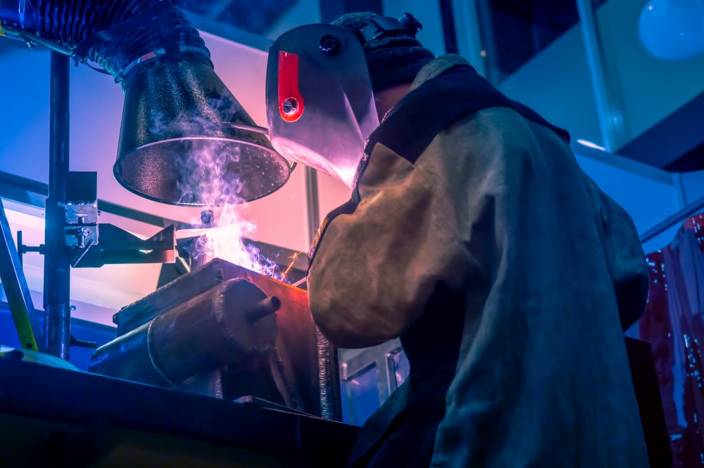 Welder welding while the fumes have been taken by the respirator safely away from the welders face