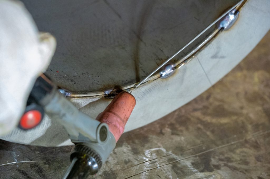 Welding of stainless steel pipe by electric arc welding in argon shielding gas. TIG welding.