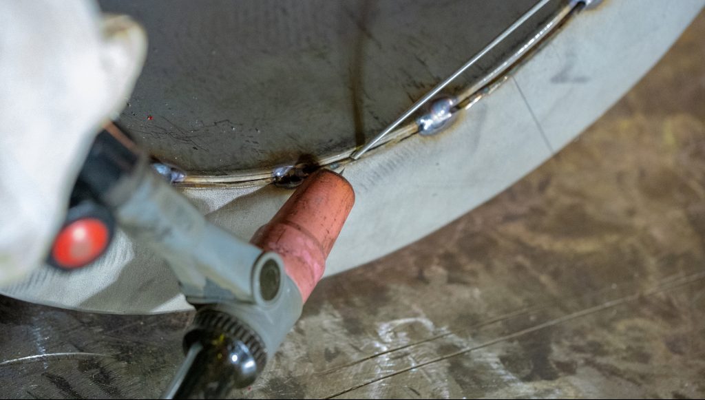 Welding of stainless steel pipe by electric arc welding in argon shielding gas. TIG welding.