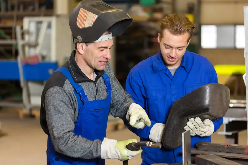 Two welders explaining one another how to use passive welding helmet.