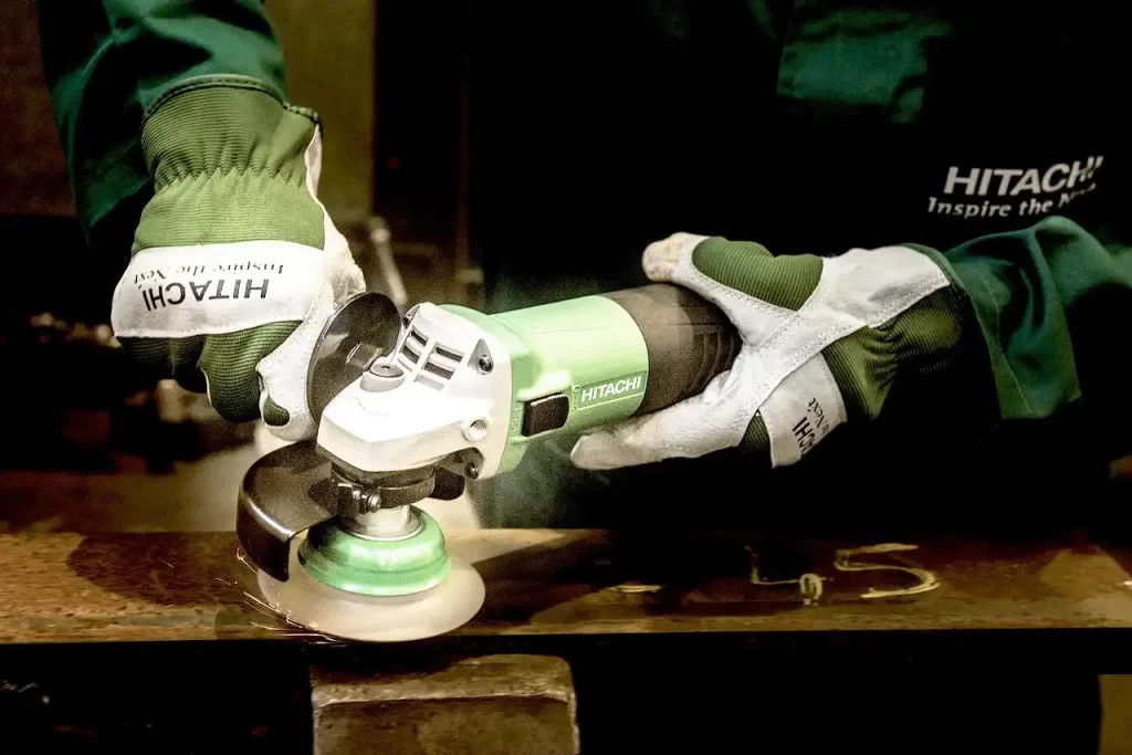 Image of a worker using a wire brush wheel on an angle grinder to grind off the rust.