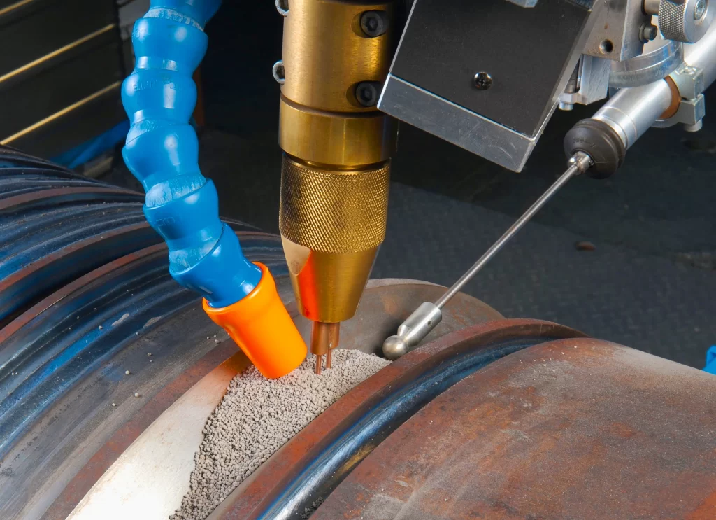 Image of a Submerged Arc Welder's welding torch and flux hopper in action on a pipe welding