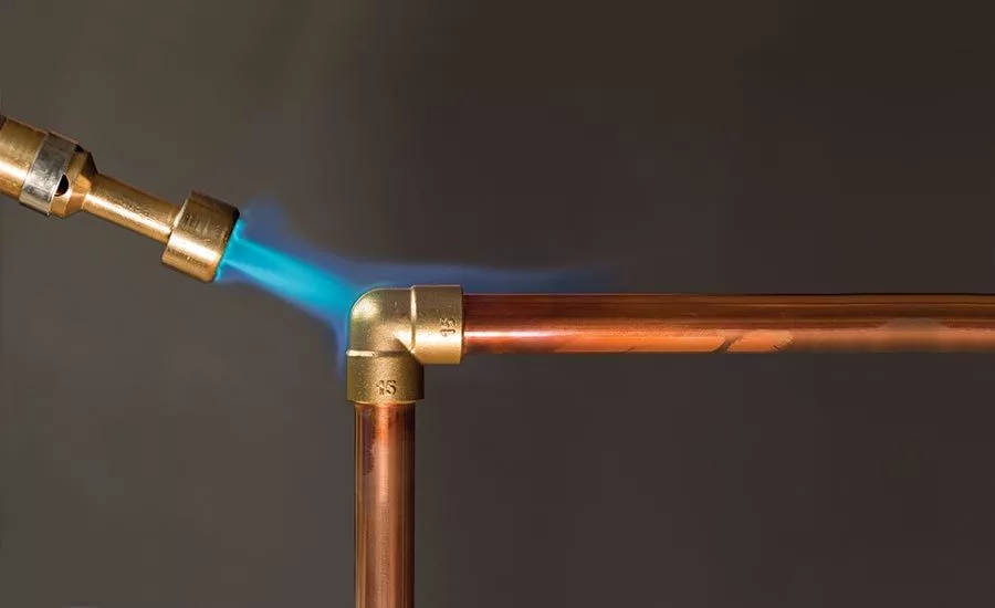 Image of a brazing torch heating the copper pipe.