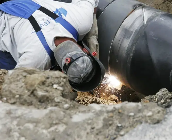 image of a welder in the field welding a pipe