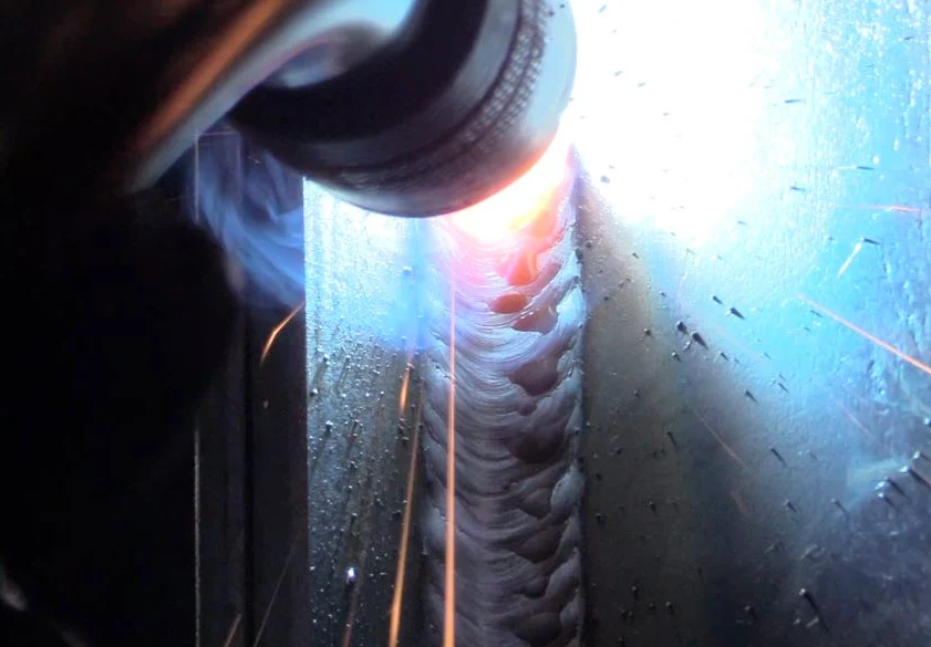 Image of a welder applying a dual shield welding process on a vertical welding bead.