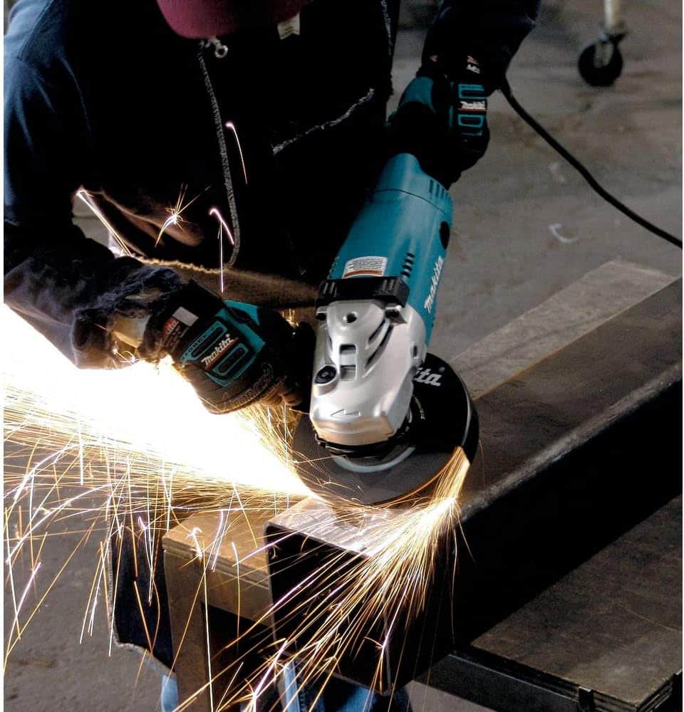 Makita GA7021 angle grinder being used on a steel workpiece
